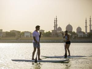 two people are standing on paddle boards in the water at Fairmont Bab Al Bahr in Abu Dhabi