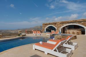 a villa with a swimming pool and lounge chairs at Aegean Villas Ios in Ios Chora