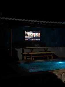 a dark room with a table and a television at Bangalô raizes in São Gonçalo do Amarante