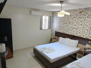 a bedroom with a bed with white sheets and a wall at Hotel Ouro de Mauá in Mauá