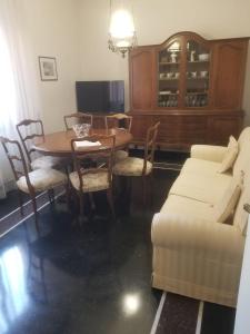 een woonkamer met een tafel en stoelen en een televisie bij Casa Carrara in Genua