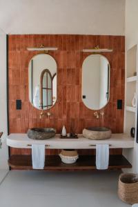 a bathroom with two sinks and two mirrors at Alma Villas in Paliton