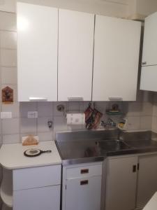 een keuken met witte kasten en een spoelbak bij Casa Carrara in Genua
