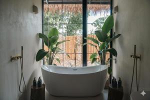 a bath tub sitting in a room with a window at Alma Villas in Paliton