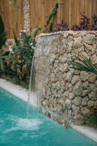 einen Brunnen in einem Pool neben einer Steinmauer in der Unterkunft Alma Villas in Paliton