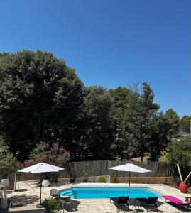 a swimming pool with two umbrellas and chairs at Esprit CAP FERRET in Puget