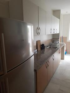 エル・ハーフラにあるSables d'or flat apartementのステンレス製の冷蔵庫とキャビネットを備えたキッチン