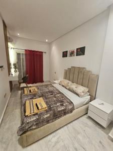 エル・ハーフラにあるSables d'or flat apartementのベッドルーム1室(大型ベッド1台、赤いカーテン付)
