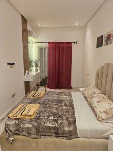 エル・ハーフラにあるSables d'or flat apartementの赤いカーテンが備わる客室の大型ベッド1台分です。