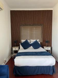 a bedroom with a large bed with blue pillows at Musgrave Escape in Durban +4 photos