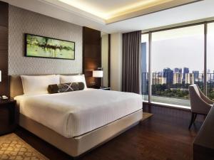a bedroom with a large bed and a large window at Fairmont Jakarta in Jakarta