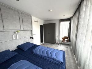 a bedroom with a blue bed and a chair at De Maasterp - Watervillage 21 in Ohé en Laak
