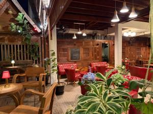 清迈Khom Chiang Mai的一间设有红色椅子和桌子的餐厅,种植了植物