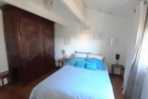 a bedroom with a white bed with blue sheets at Au Jardin Des Couleurs in Pierrefeu-du-Var