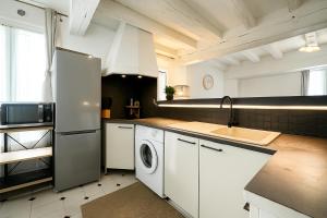 a kitchen with a refrigerator and a washing machine at Grace Even's Loft - Charme Médiéval & Confort Moderne - Wi-Fi Fibre, Netflix & Cuisine Équipée - Séjour Idéal en Duo ou Solo in Donnemarie-en-Montois