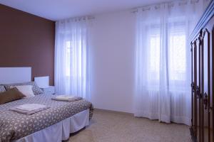 a bedroom with a bed and a window with white curtains at La Corte Del Pane in Corridonia