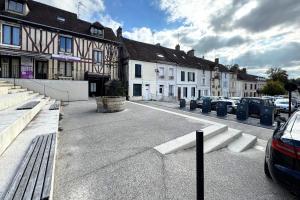 a street in a town with buildings and cars at Grace Even's Loft - Charme Médiéval & Confort Moderne - Wi-Fi Fibre, Netflix & Cuisine Équipée - Séjour Idéal en Duo ou Solo in Donnemarie-en-Montois