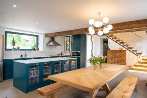 a kitchen with blue cabinets and a wooden table at Les GRANDS enfants - 1h15 de Paris - Piscine intérieure chauffée - Offres Pro in Subligny
