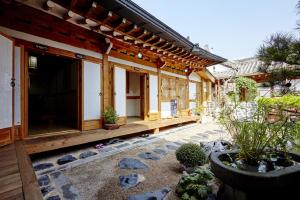 Happiness Full Hanok Guesthouse في جيونجو: مبنى فيه فناء فيه نباتات وصخور
