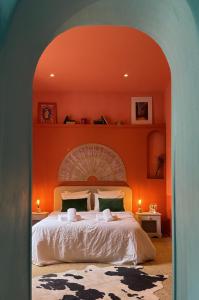 a bedroom with a large bed with an orange wall at La Casa De Frida charme & poésie in Narbonne +9 photos