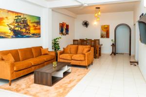 una sala de estar con muebles naranjas y un cuadro de un barco en Villa Tuskaara, en Tangalle