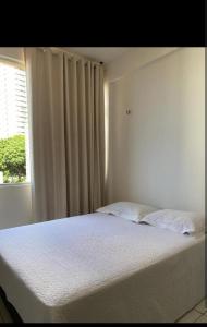 a white bed in a room with a window at Luxo in Caruaru