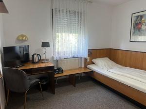 a bedroom with a bed and a desk with a computer at Hotel Neue Traube in Fellbach