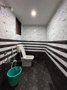 a bathroom with a toilet and a green bucket at Gajalee Beach House in Bhogwe