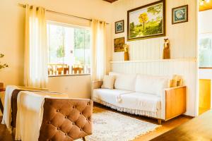 a living room with a couch and a window at Pousada Jardim da Mantiqueira in Monte Verde
