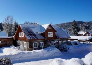 une grande maison en bois recouverte de neige dans l'établissement Chalet Schäfer s vyhřívaným bazénem se slanou vodou, à Harrachov