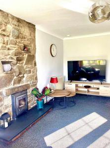 a living room with a stone fireplace and a television at Ty Newydd in Llangyniew
