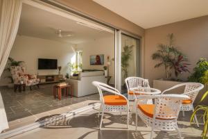 a living room with white chairs and a table at Da Alohas Hibiscus Oasis Pool Facing Candolim in Betim