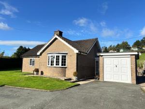 a brown brick house with a white garage at Ty Newydd in Llangyniew