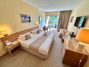 a hotel room with a large bed and a desk at Hôtel La Pinède in Ajaccio