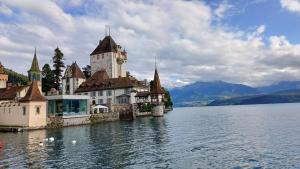 a building on the shore of a lake with a clock tower at Lakeview Lodge Ferienwohnung Aeschlen ob Gunten am Thunersee in Aeschlen ob Gunten