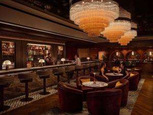 a bar with people sitting at tables and chandeliers at Fairmont Singapore in Singapore