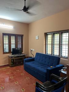 a living room with a blue couch and a tv at Tharissu potta farm stay in Kollengode
