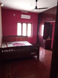 a bedroom with pink walls and a wooden bed at Tharissu potta farm stay in Kollengode