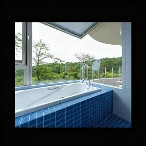 a bath tub in a bathroom with a window at Wyndham Garden Nagaizumi in Numazu