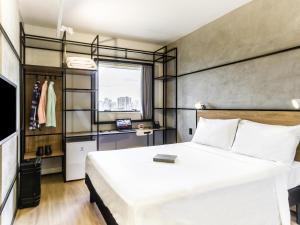 a bedroom with a large white bed and a window at ibis Ribeirao Preto Vila do Golf Shopping in Ribeirão Preto