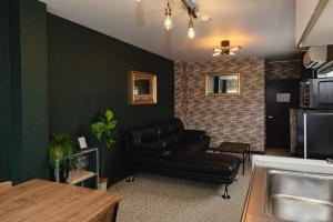 a living room with a leather couch and a kitchen at Darin博多 in Fukuoka