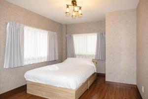 a bedroom with a white bed and two windows at Darin博多 in Fukuoka