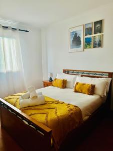 a bedroom with a large bed with yellow pillows at Ocean Gardens in Caniço