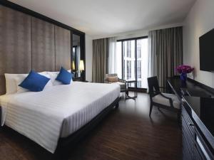 a bedroom with a large bed with blue pillows at Mövenpick Hotel Sukhumvit 15 Bangkok in Bangkok
