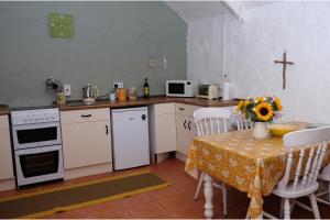 a kitchen with a table with a vase of flowers on it at Cottage Sleeps 2- Parking Wood Fire Garden Pets in Lizard +37 photos