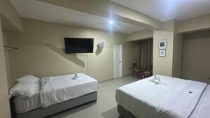 ein Schlafzimmer mit zwei Betten und einem Fernseher an der Wand in der Unterkunft MOON Edificio in San Vicente de Cañete