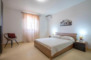 a bedroom with a bed and a chair in it at Villa Giovanna in Marina di Sorso