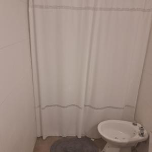 ein Badezimmer mit einem weißen Duschvorhang und einem WC in der Unterkunft Departamento Ituzaingo in Rafaela