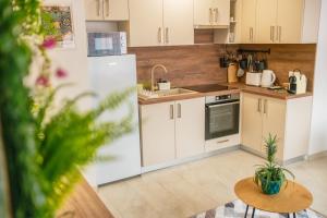 a kitchen with white cabinets and a sink and a table at ARKSIS Apartman in Sárvár +7 photos