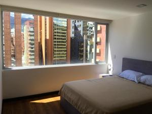 a bedroom with a bed and a large window at Apartamento Finlandia Park Suite in Quito